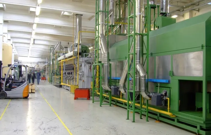 Línea de producción en una planta industrial con maquinaria y montacargas