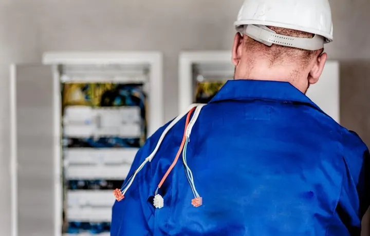 Técnico trabajando frente a tableros eléctricos en una sala de control